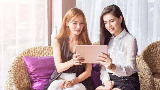 Two working women refer to the tablet during discussion 