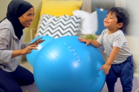 Mother playing blue yoga ball with kid