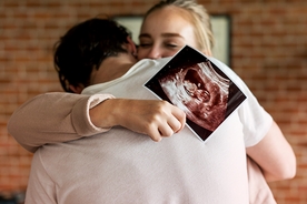 Happy parents holding week 5 pregnancy ultrasound scan