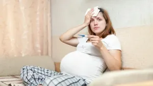 pregnant-woman-with-thermometer-living-room