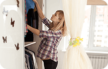 Pregnant woman looking through her clothes in the wardrobe 