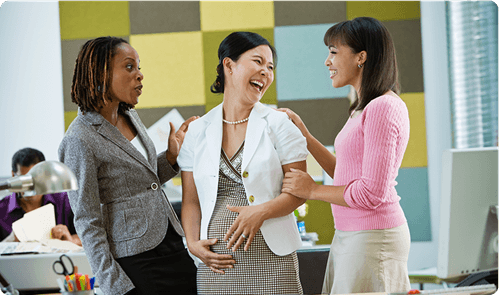 Expectant woman embracing pregnancy fashion while interacting with her colleagues