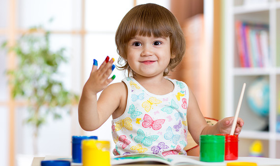 A toddler painting with his fingers