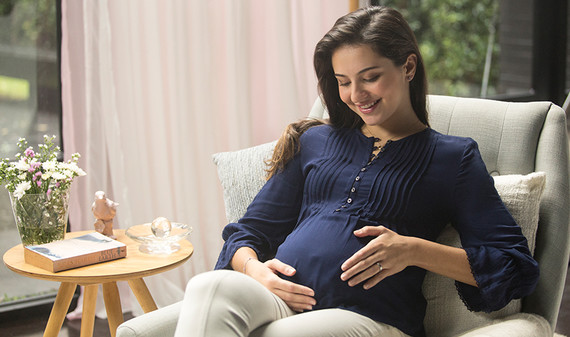 Pregnant lady is relaxed, looking affectionately at her baby in her womb