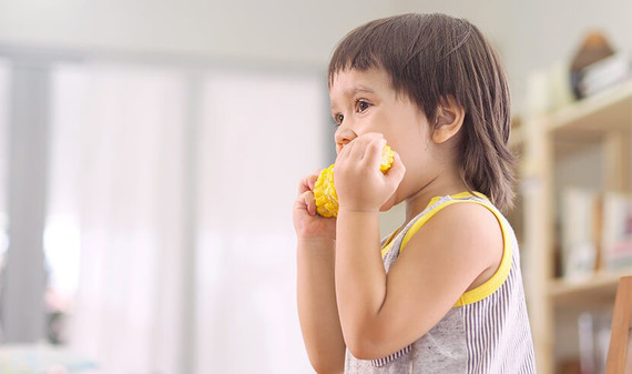 Kid is eating corn to ensure sufficient of nutrients