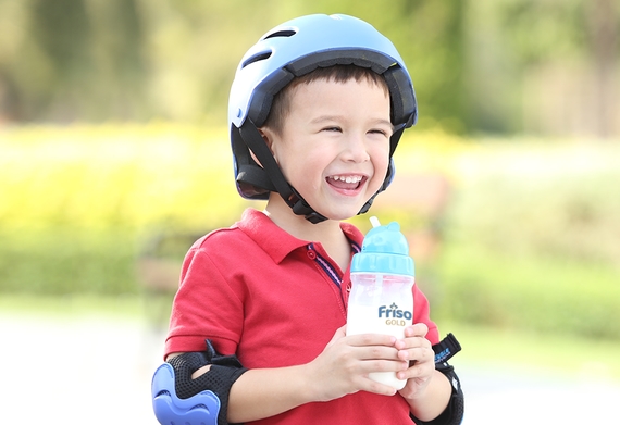 Red shirt kid holding Friso Gold formula milk