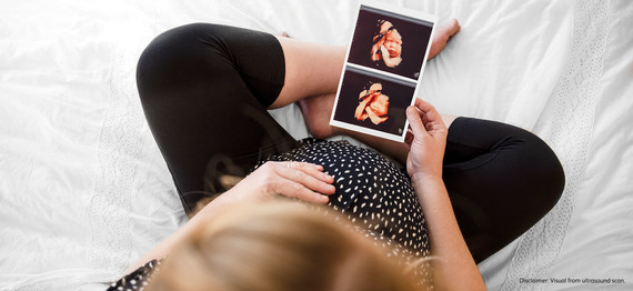 Pregnant Woman looking at her ultrasound scans showing monthly development of her fetus