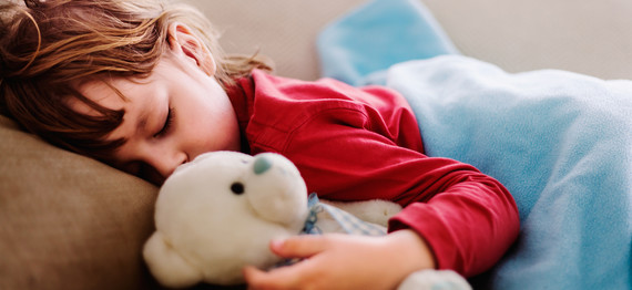 A sleeping child with teddy bear in hand