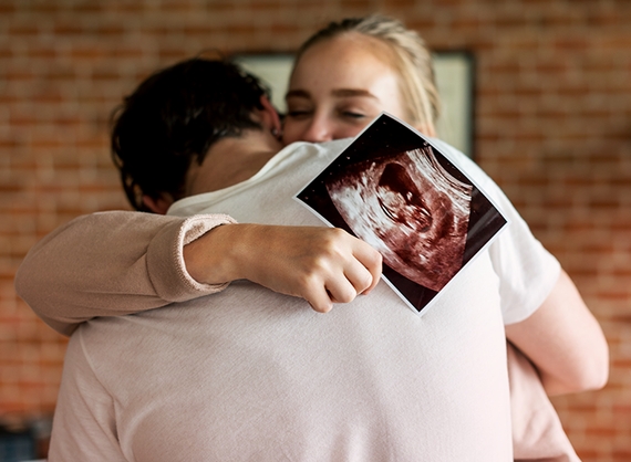 Happy parents holding week 5 pregnancy ultrasound scan