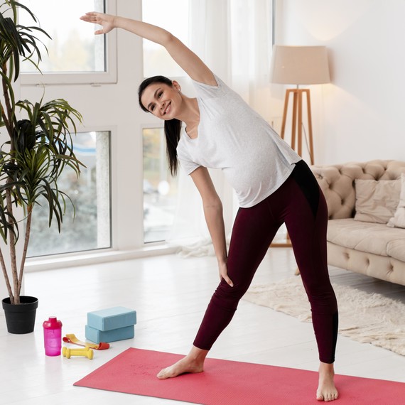 Young pregnant woman exercising on yoga mat
