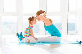 Mother plays and interacts with her child while doing yoga work out 