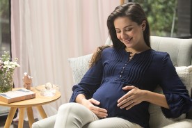Pregnant lady is relaxed, looking affectionately at her baby in her womb