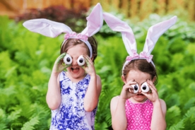 Two girls with animal ear hairbands holding up homemade animal eyes infront of their faces