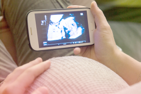 Pregnant woman viewing the baby ultrasound scan in mobile phone