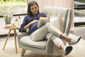 Pregnant woman sitting on sofa reading a book