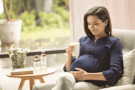 A mother holding a cup of maternal milk