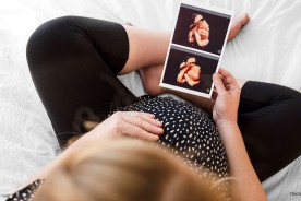 Pregnant Woman looking at her ultrasound scans showing monthly development of her fetus