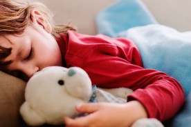 A sleeping child with teddy bear in hand