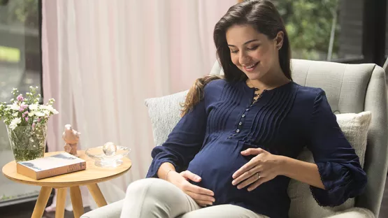 Pregnant lady is relaxed, looking affectionately at her baby in her womb