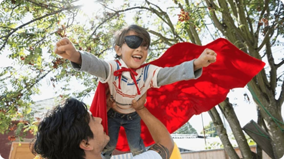 A child is playing super hero flying game with father