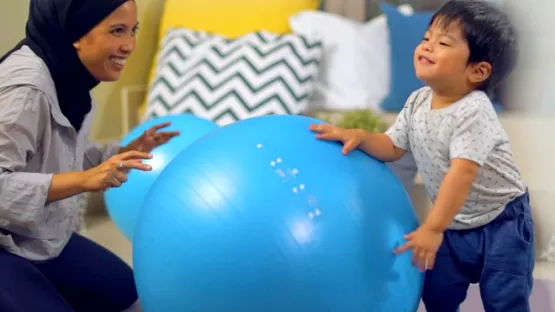 Mother playing blue yoga ball with kid