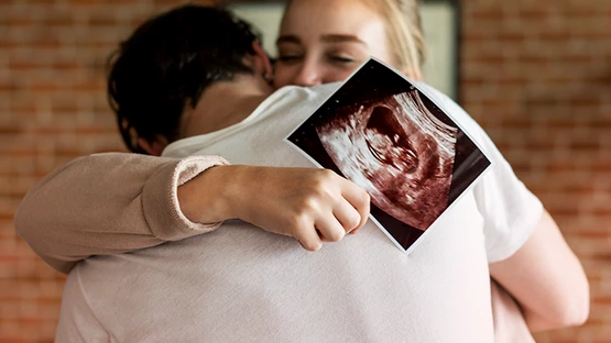 Happy parents holding week 5 pregnancy ultrasound scan