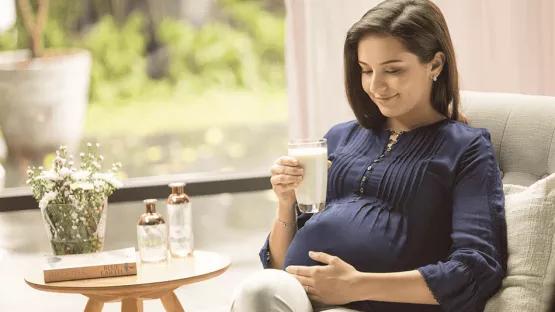 A mother holding a cup of maternal milk