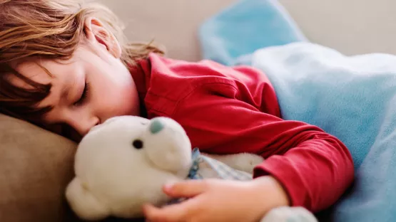 A sleeping child with teddy bear in hand