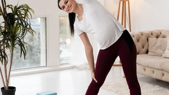 Young pregnant woman exercising on yoga mat