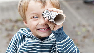 A child pretending to look through a telescope with a toilet roll