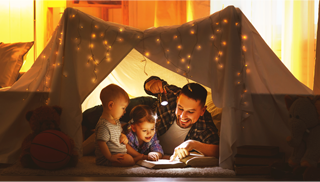 A father and his children in a home tent pretending to camp out in the wild