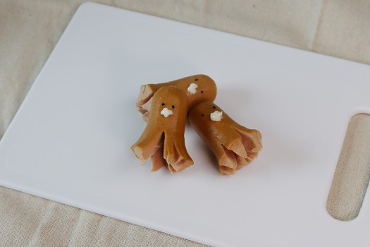 Cooked sausages with curled legs decorated with sesame seeds and mayonnaise to create mini faces
