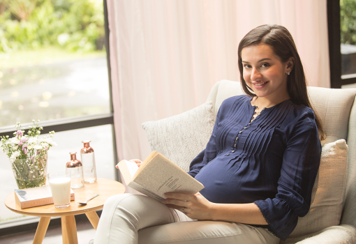 Pregnant woman reading book on importance of maternal milk